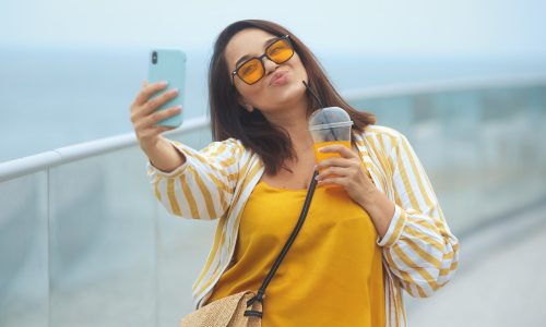 Cheerful and happy young overweight brunette woman 30-35 years old makes a selfie on a mobile phone