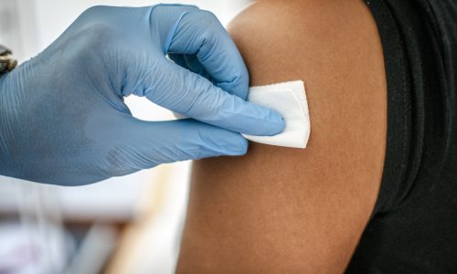 Doctor disinfects skin of patient before vaccination