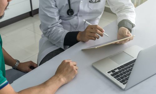 Doctor is consulting with Patient about his health on working desk